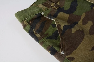 Close-up of classic camouflage cargo pants showing waist details and metal rivets