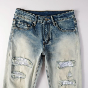 Dettaglio dei jeans azzurri con toppe di strass luccicanti e stile streetwear