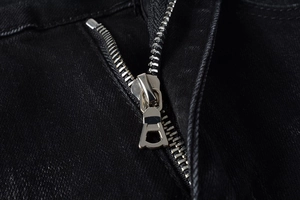 Close-up of durable metal zipper and reinforced stitching on black slim fit denim jeans