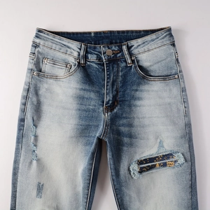 Detail of ripped jeans with vintage floral patch and heavy washed blue denim fabric