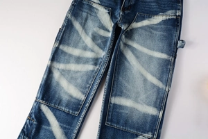 Detail of bleached wash pattern and side utility loop on blue utility cargo jeans