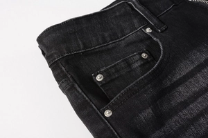Detail view of washed black denim jeans showing metal rivets and reinforced stitching