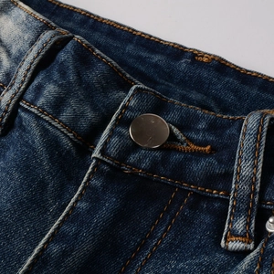 Détail de la taille avec bouton en métal et coutures orange sur un jean bleu