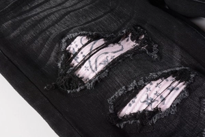 Detail of distressed black denim with pink paisley bandana patchwork and frayed edges