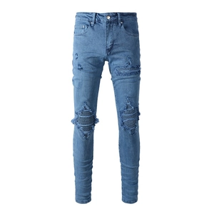 Détail de jean slim bleu délavé avec déchirures aux genoux et empiècements rayés