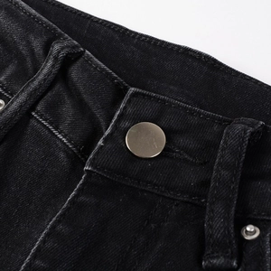 Detailed macro view of black denim waistband featuring metal buttons and reinforced loops