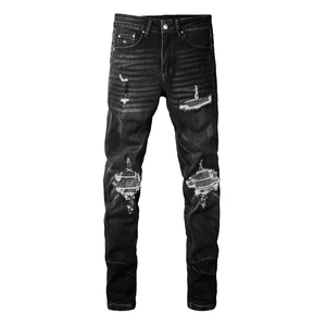 Detail of ripped patches and whiskers on washed black slim fit denim jeans for men