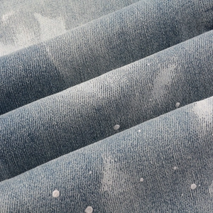 Macro view of light blue denim fabric with white splatter print and twill texture