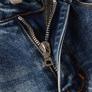 Detail of vintage blue jeans showing silver metal zipper and orange contrast stitching