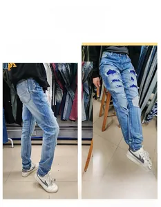 Close-up of light blue distressed jeans with sequins inner patch and ripped details