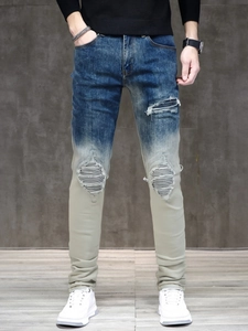 Detail of slim fit gradient jeans with ripped knee patches and black striped lining