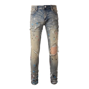 Slim fit men's street style distressed denim jeans with paint splatters and ripped knees