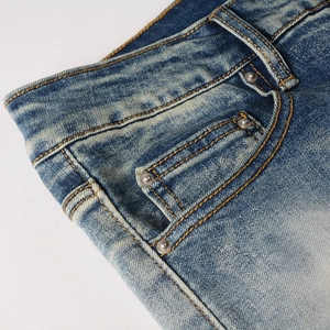 Dettaglio ravvicinato della vita di jeans blu con rivetti metallici e cuciture arancioni