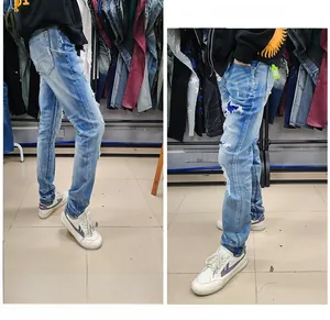 Detail of men's slim fit distressed jeans featuring blue star sequins and paint splatters