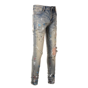 Slim fit men's street style distressed blue denim jeans with paint splatters and ripped knee