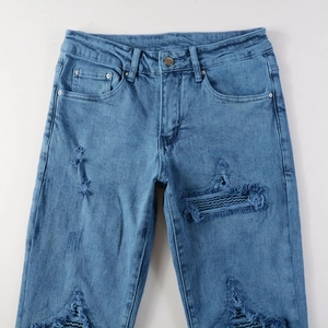 Gros plan sur un jean déchiré avec des patchs en tissu rayé et des détails usés