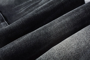 Gros plan sur le denim sergé gris foncé de haute qualité et la texture délavée du jean