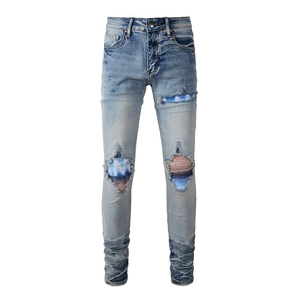 Detail of light blue men's stacked jeans with striped patches in distressed holes