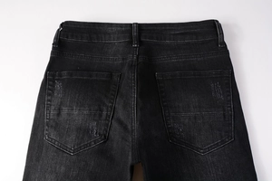 Detail of back pockets on black washed denim jeans with distressed and ripped craftsmanship