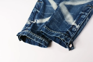Detailed macro view of denim hem with white cross print and silver metal button detail