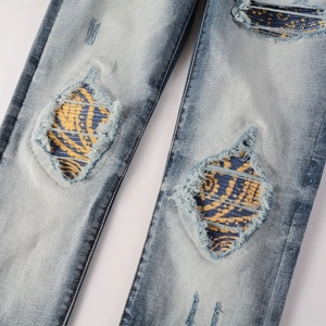 Macro shot of light blue washed jeans with distressed details and paisley patchwork