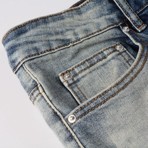 Détail de jean bleu délavé vintage avec coutures jaunes et rivets métalliques