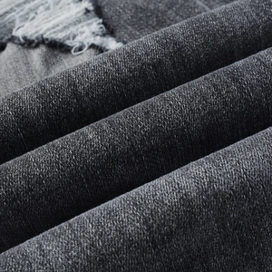 Vue macro de la texture du denim noir avec détails de bords déchirés et usés