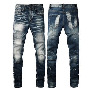 Slim fit men's distressed blue jeans with paint splatter and faded whisker patterns