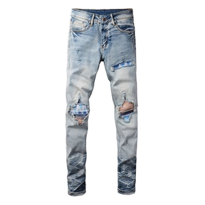 Detail of distressed light blue jeans with colorful striped patchwork inside leg holes