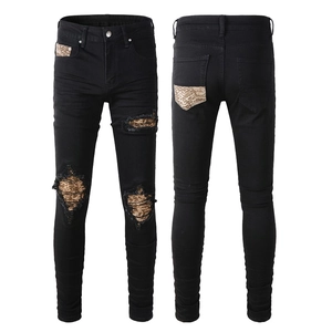 Detail view of slim black jeans with leopard print patches and distressed ripped knees