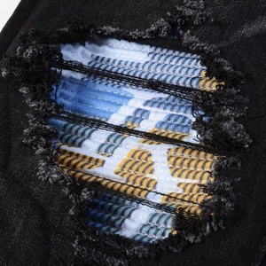 Macro shot of black denim distressed jeans with colorful wave pattern repair detail