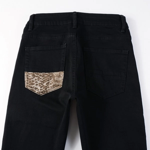 Detail view of black denim jeans featuring leopard print patch on the back pocket