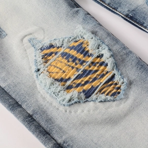 Men's vintage slim stretch jeans in light blue featuring retro striped patch and distressed holes