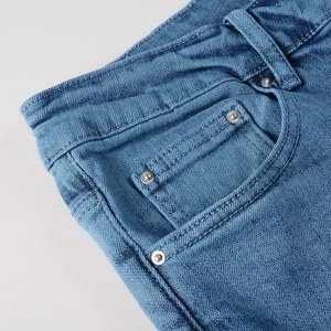 Détail du tissu denim bleu montrant la taille robuste, les passants et les rivets