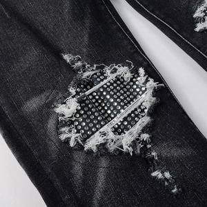 Slim fit black distressed denim jeans with rhinestone patches and frayed hole details