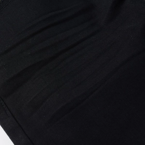 Macro shot of black denim fabric detailing high-density twill and distressed whiskering