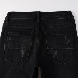 Detail of back pockets on black slim jeans with washed texture and decorative stitching
