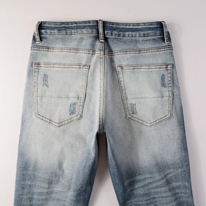 Detail of distressed back pockets on vintage blue wash slim fit denim jeans for men