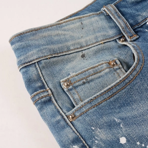 Detailed macro view of denim fabric with paint splatters and orange contrast stitching