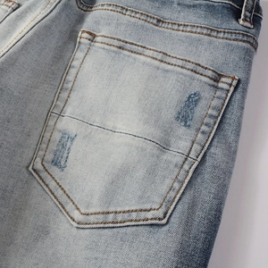 Detail of light blue denim jeans showing vintage distressed pocket and orange stitching