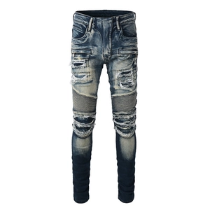 Macro detail of biker jeans with distressed denim, pleated panels, and metal zippers