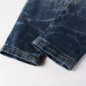 Gros plan de l'ourlet du jean bleu délavé avec texture marbrée et coutures orange