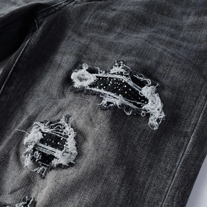 Détail du jean vieilli avec des strass noirs et des finitions à bords effilochés