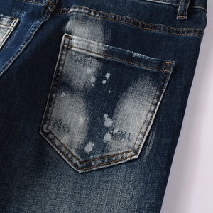 Dettaglio jeans vintage blu scuro con effetto lavaggio bianco e dettagli di vernice