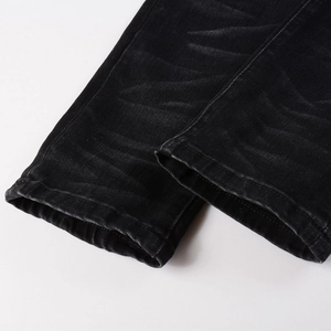 Close-up of black denim jeans hem showing washed effect and high-quality stitching details