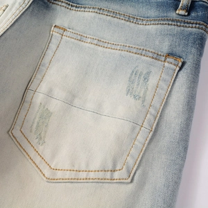 Dettaglio della tasca posteriore in denim lavaggio acido azzurro con cuciture arancioni