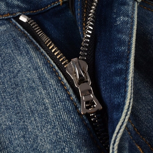 Detail of high-quality silver metal zipper on vintage washed blue denim jeans