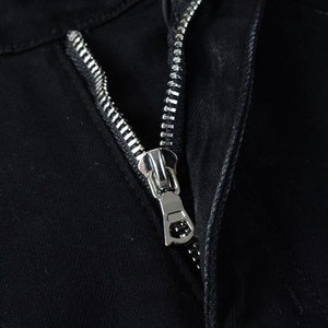 Macro shot of a high-quality silver metal zipper on black slim fit denim trousers