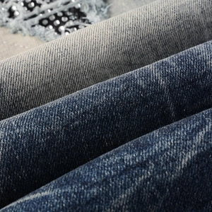 Gros plan d'un jean en denim usé avec des strass argentés et une texture délavée