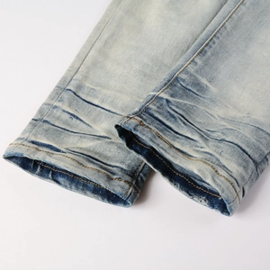 Dettaglio dell'orlo dei jeans lavaggio azzurro con bordi usurati e cuciture arancioni
